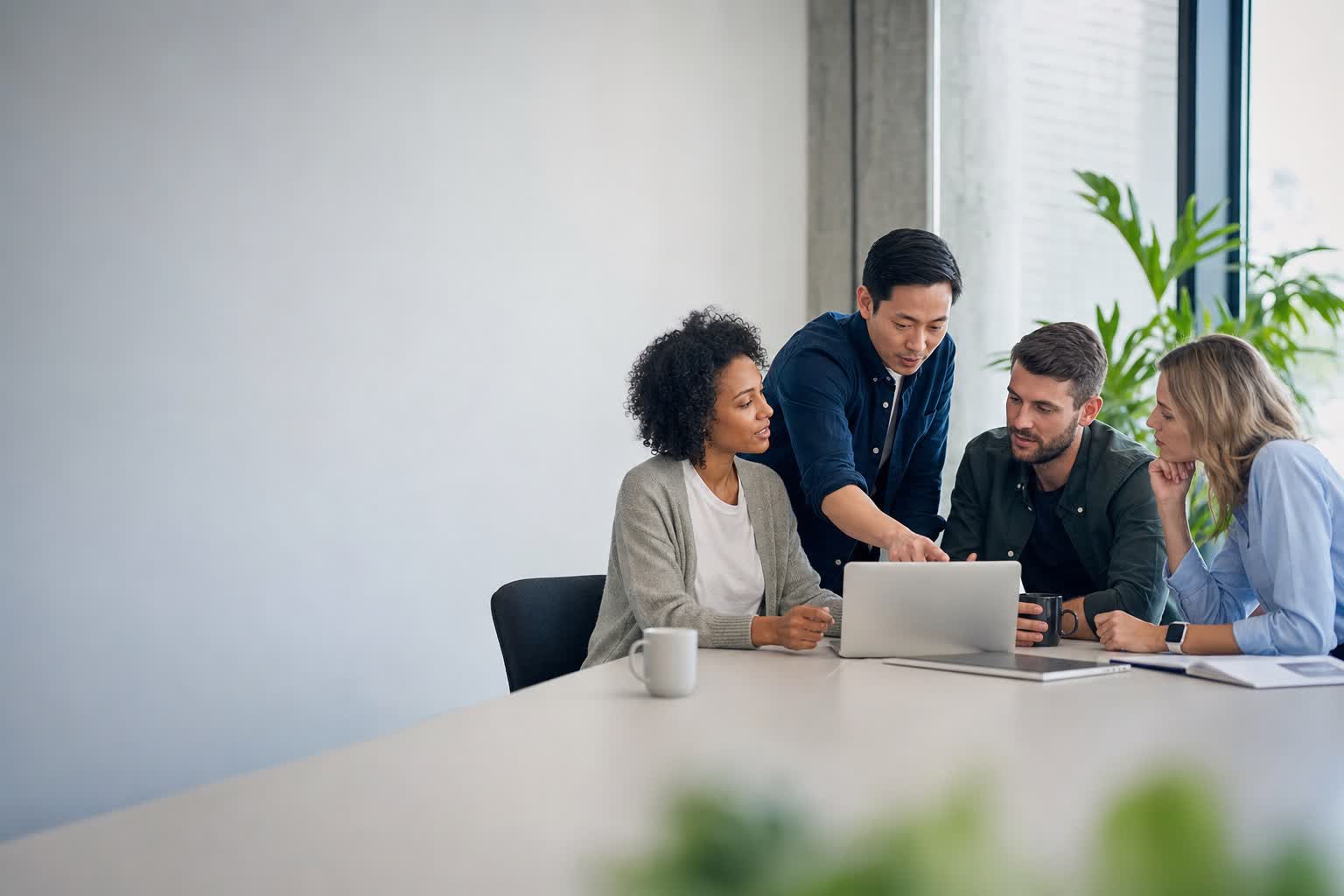 Team arbeitet gemeinsam am Laptop in einem modernen Büro