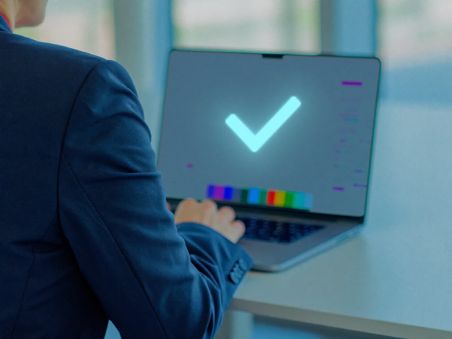 Qualitätsmanager am Laptop mit leuchtendem Häkchen-Symbol